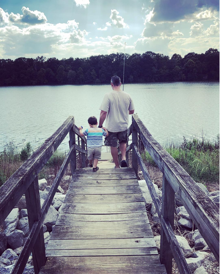 father and son walking on pier with fishing poles